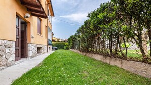 Una casa con fondamenta in pietra, un vialetto lastricato e un prato curato con fiori bianchi.