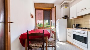 Una cucina compatta con tavolo e sedie, frigorifero, fornello e una finestra vista sul verde.