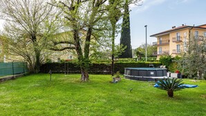 Un quartiere residenziale con giardino, alberi, piscina e un edificio con balconi.