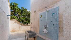 Une salle de bain avec un lavabo, une douche et un mur recouvert de carrelage.