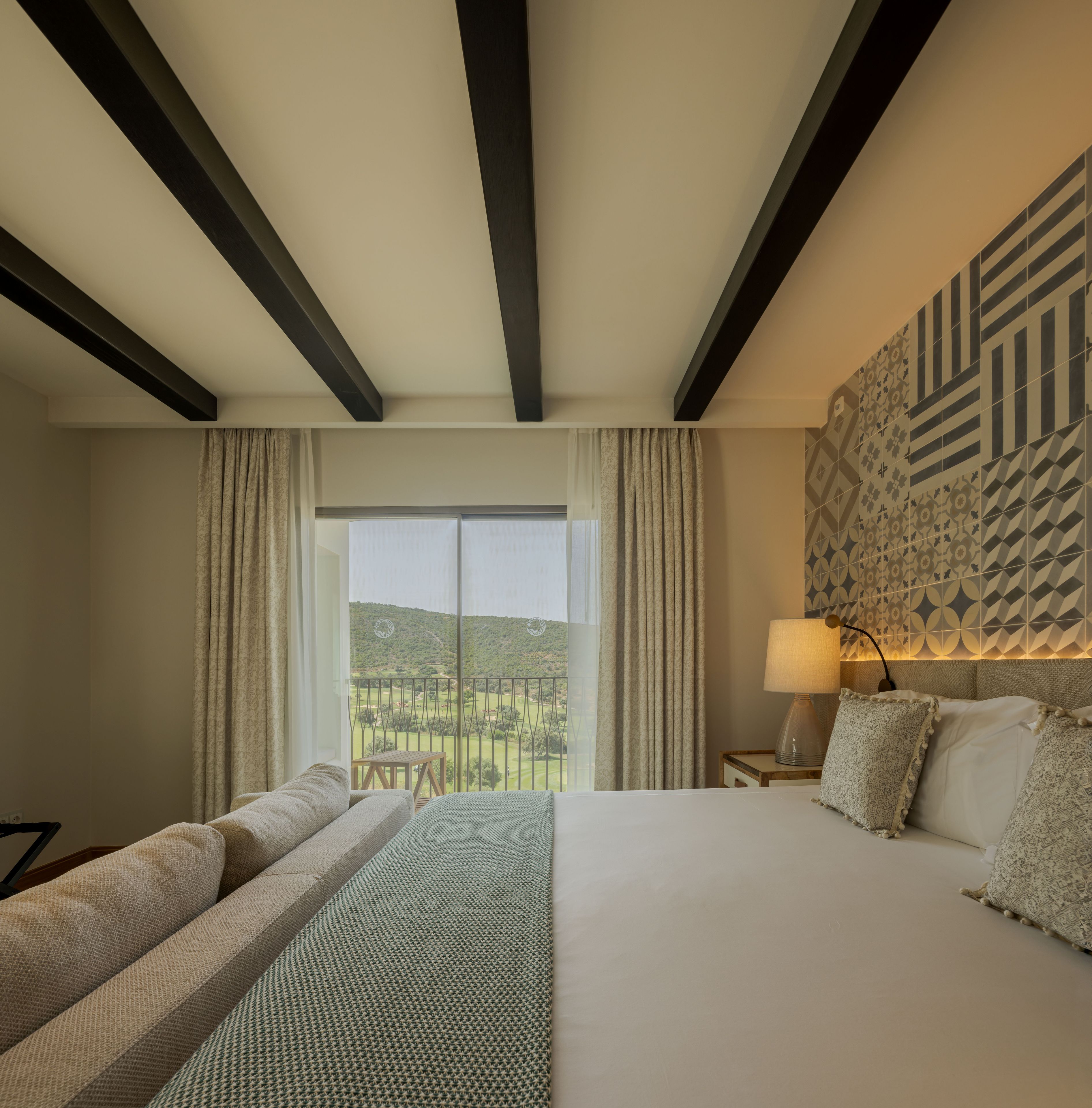 Una habitación de hotel con una cama grande, vista a un campo de golf y un papel tapiz estampado.