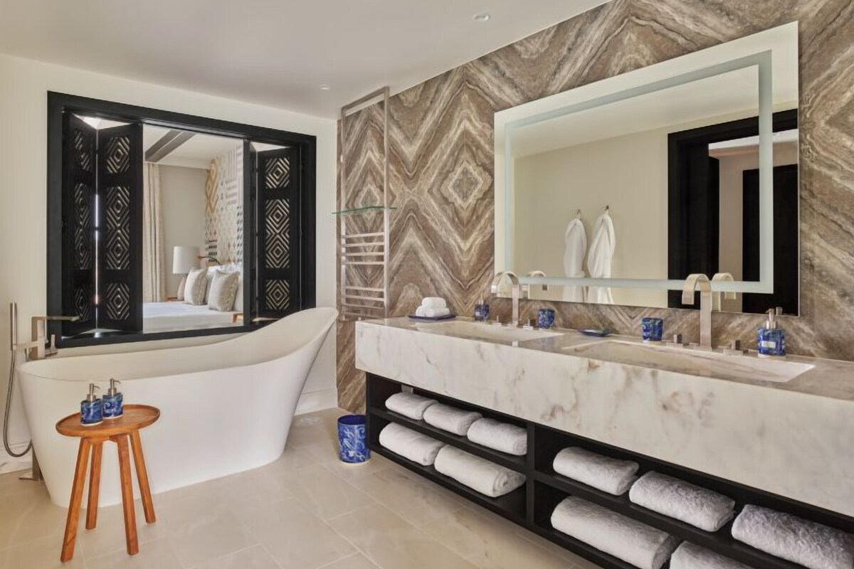 A modern bathroom with a freestanding bathtub, a large vanity with a marble countertop, and a wall-mounted mirror.