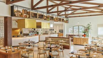 A spacious restaurant with high ceilings, exposed wooden beams, and a variety of seating arrangements including tables and booths.