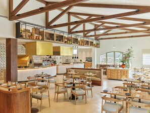 Un restaurante espacioso con techos altos, vigas de madera a la vista y diversas opciones de asientos, como mesas y cabinas.