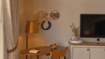 Quarto compacto com uma mesa de jantar, cadeiras, luminária, TV de tela plana e um armário.