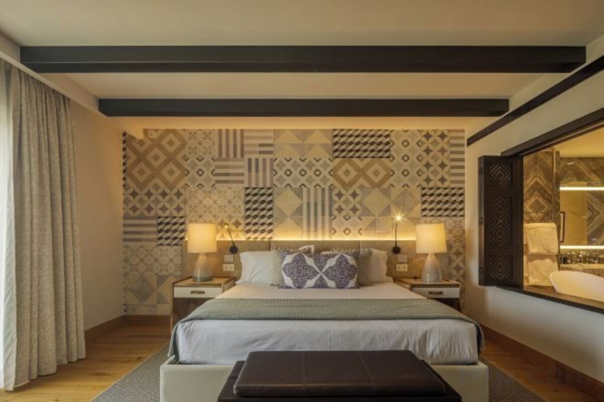 A hotel room with a bed, bedside tables, and a large window.