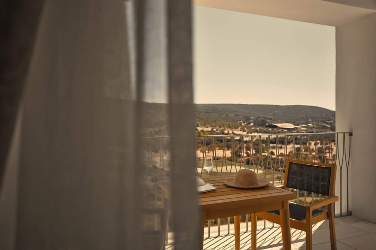 A balcony with a table and chairs, a hat, and a glass of wine.