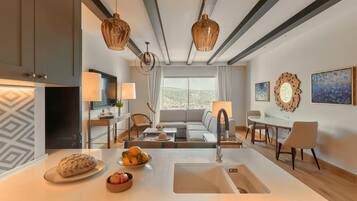 A modern kitchen with a central island, a dining area with a table and chairs, and a living room with a sofa and a view of the outdoors.