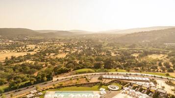 Ein Resort mit großem Poolbereich, mehreren Liegestühlen und Blick auf die umliegende Landschaft.