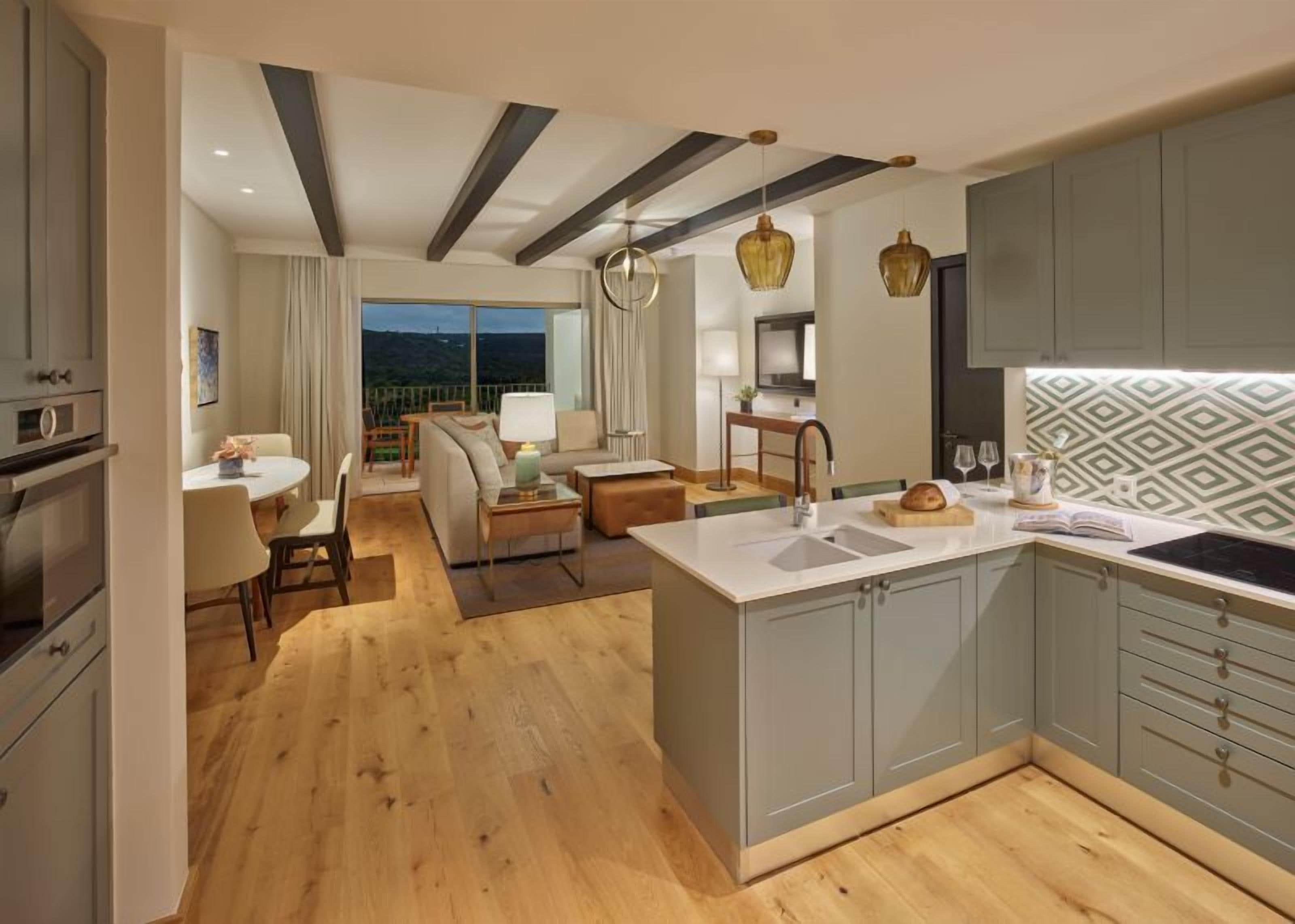 A modern kitchen with a central island, grey cabinets, and a patterned backsplash.