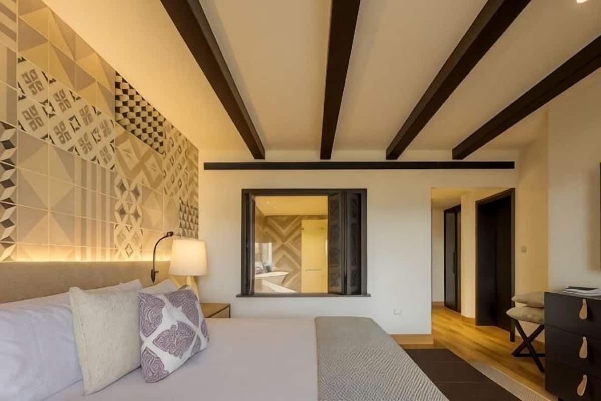 A modern hotel room with a large bed, a desk, and a mirror.