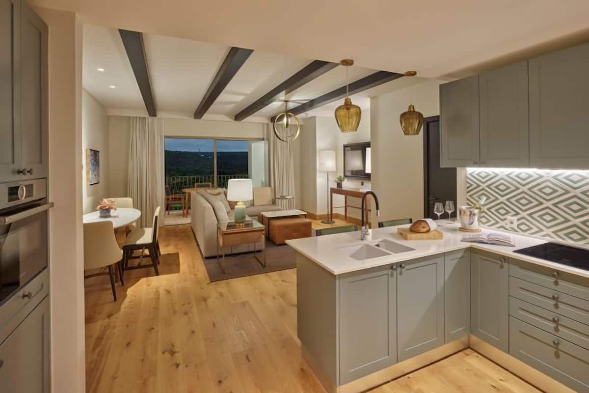 A modern kitchen with a central island, grey cabinets, and a patterned backsplash.