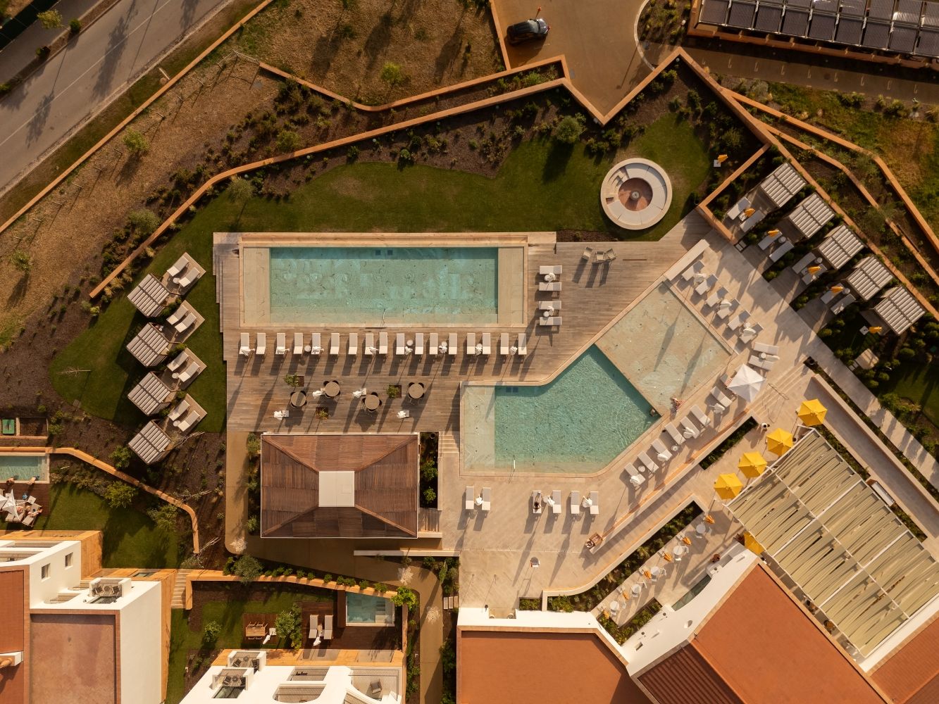 Luchtbeeld van een resort met een groot zwembad, ligbedden en een apart zwemgedeelte.