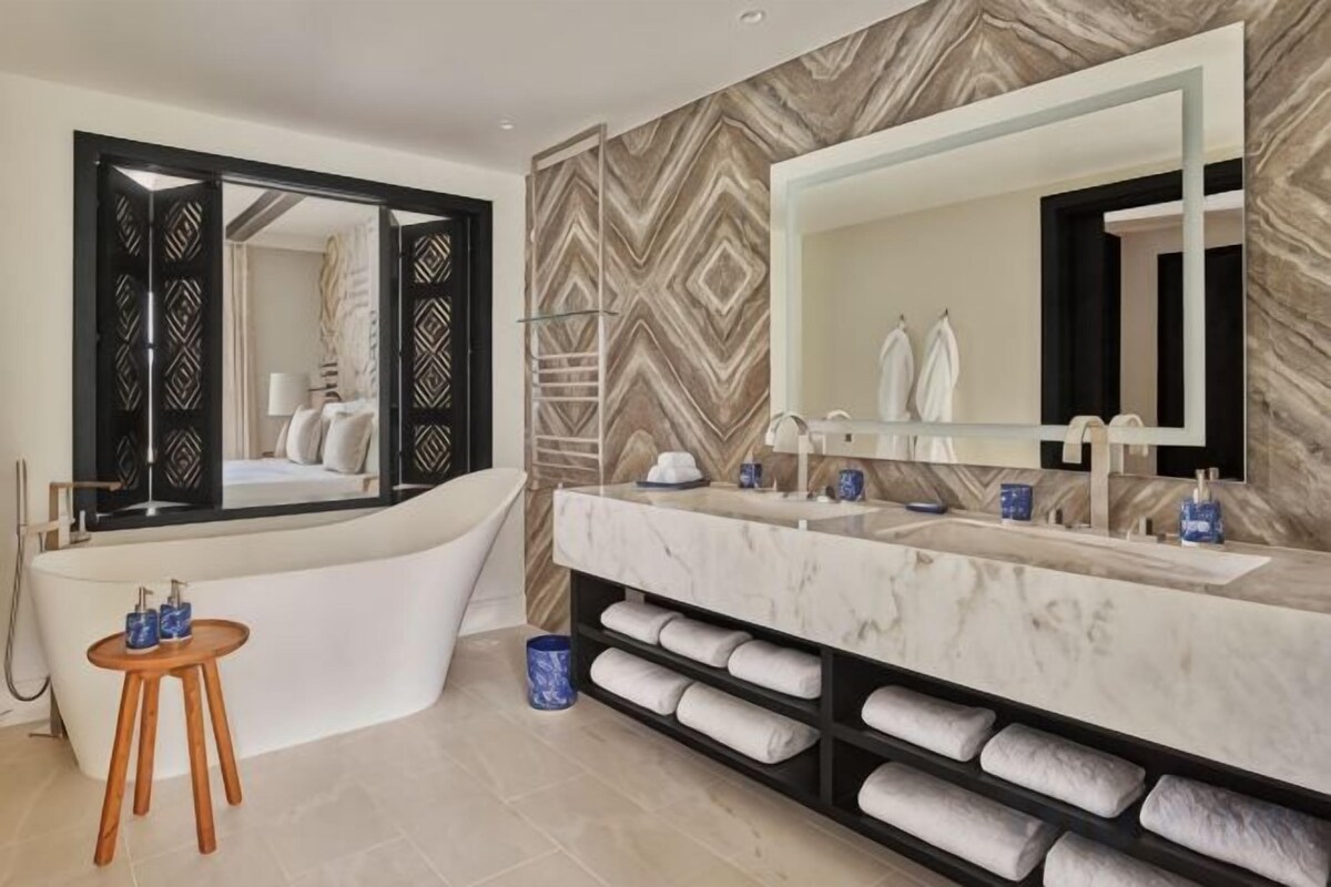 A modern bathroom with a freestanding bathtub, a large mirror, and a marble vanity.