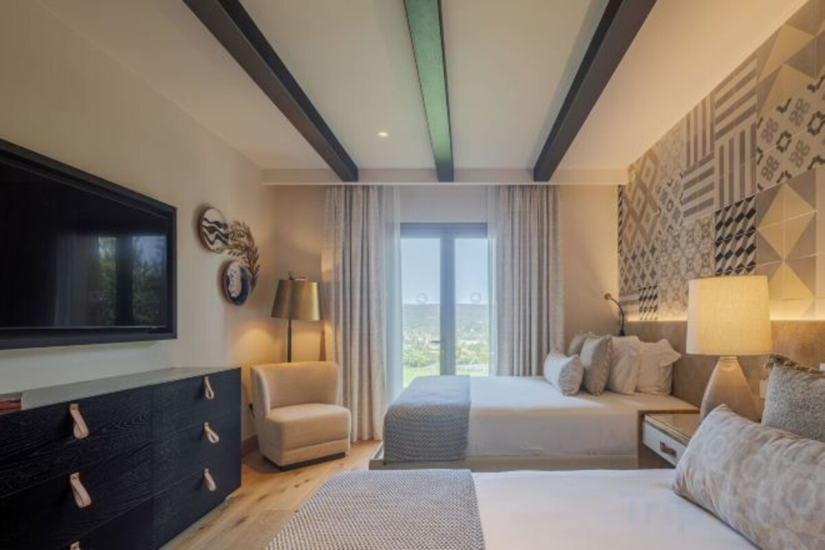 A hotel room with a bed, a TV, a desk, and a chair.