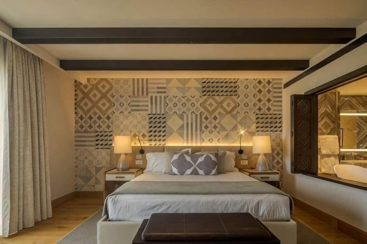 A bedroom with a bed, bedside tables, lamps, a window, and patterned wallpaper.