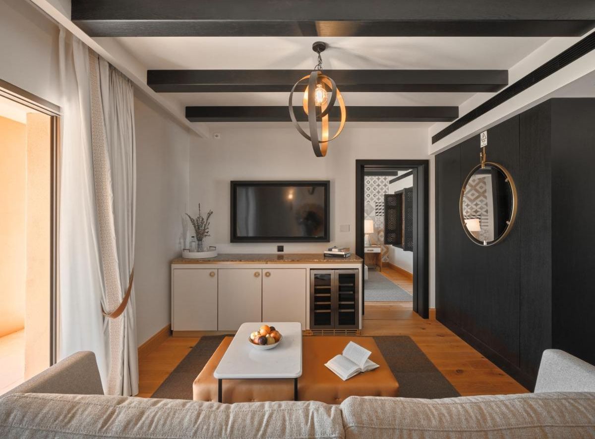 Een moderne woonkamer met een bank, een salontafel, een televisie en een keukenhoek met een eettafel en kasten.