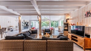 A spacious living room with a large sectional sofa, a television, and a wooden entertainment unit.