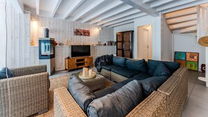 A modern living room with a large sectional sofa, a television, and a fireplace.