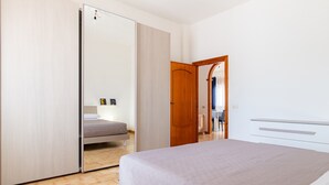 Une chambre à coucher comprenant un lit, une armoire et une porte donnant sur une autre pièce.