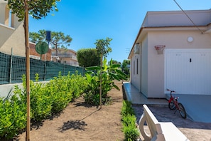 Um bairro residencial com um cesto de basquete, uma bicicleta e uma casa com porta branca.