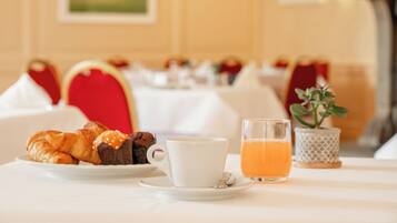A breakfast setting with croissants, a cup of coffee, and a glass of orange juice on a table.