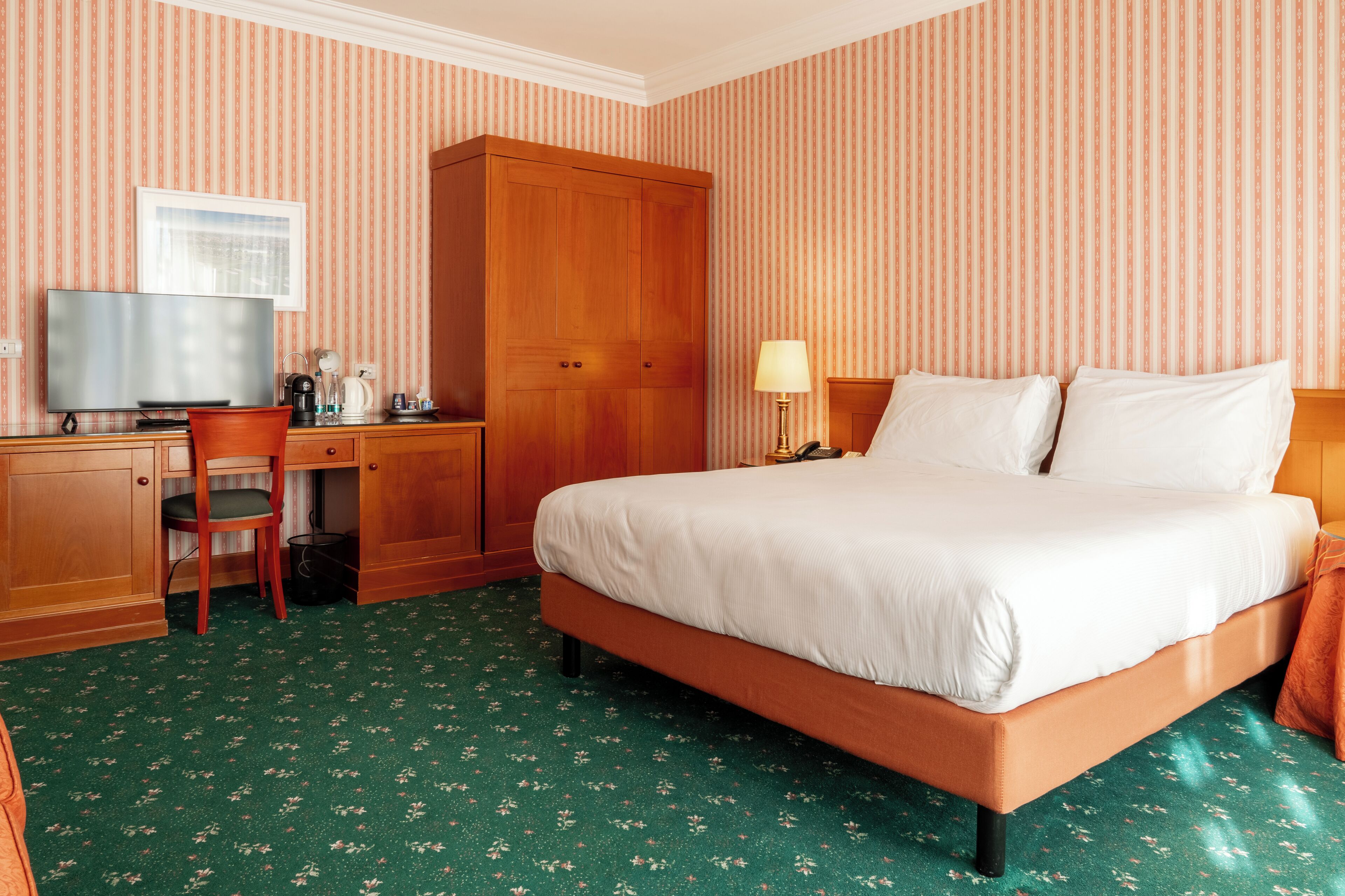 Une chambre d’hôtel équipée d’un lit, d’un bureau, d’une télévision et d’une armoire.