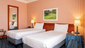 Habitación de hotel con dos camas, papel tapiz a rayas, un cuadro en la pared y dos mesitas de noche con lámparas.