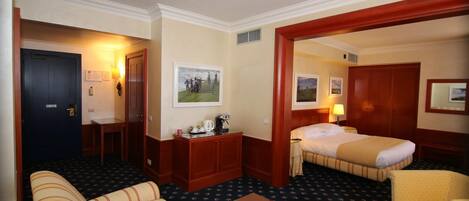 A hotel room with a bed, a sofa, a desk, and a chair.