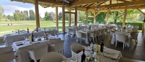Un restaurante al aire libre con mesas dispuestas para comer, con vistas a un campo de golf.
