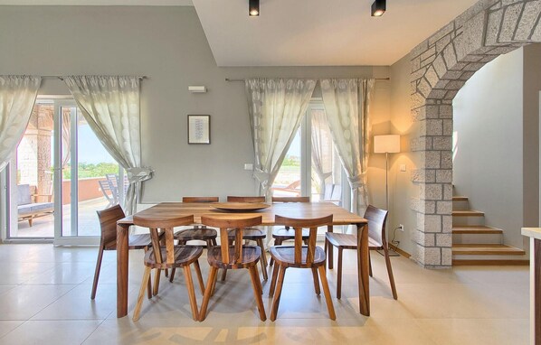 Un comedor con mesa y sillas de madera, una escalera de piedra y vistas al exterior.