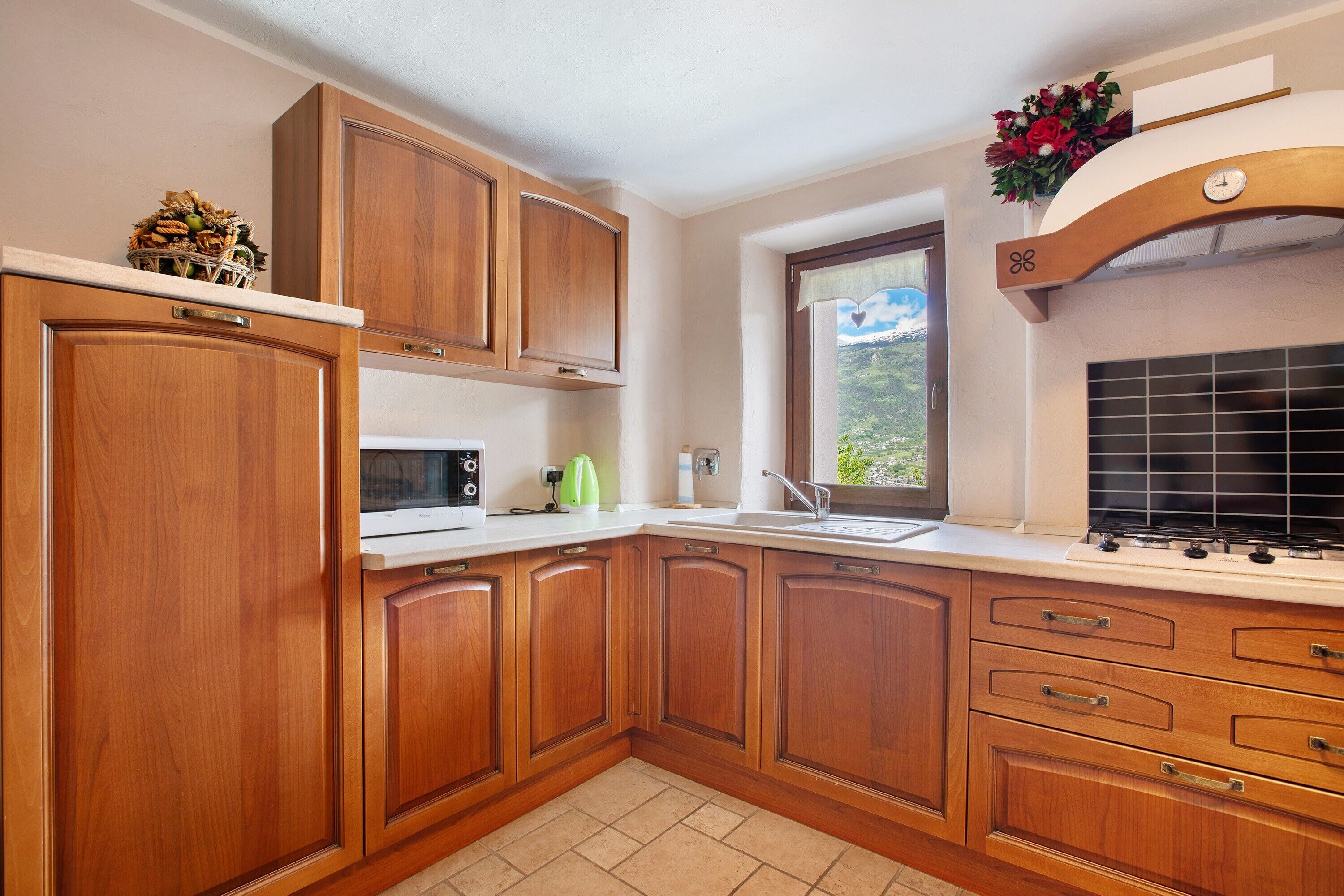 Una cocina con armarios de madera, microondas, lavabo y ventana con vistas.