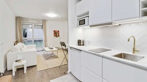 Cozinha moderna com armários brancos, micro-ondas, torradeira e pia.