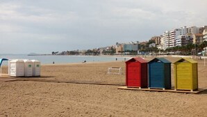A beach with beach huts and a soccer goal.