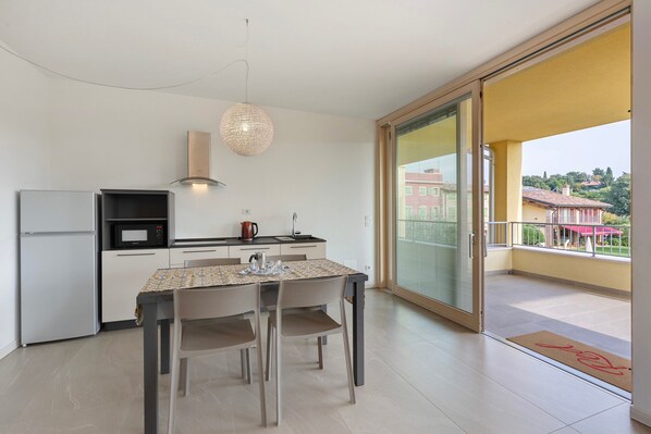 A modern kitchen with a dining table, chairs, a microwave, and a hanging light fixture.