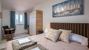 A bedroom with a bed, a chair, a wardrobe, a painting, and a window with curtains. - Gorgeous home in Ugljan (Ugljan)
