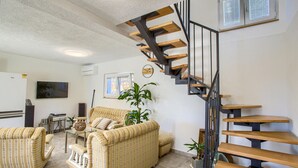 A living room with a striped sofa, a glass coffee table, and a wooden staircase. - Gorgeous home in Ugljan (Ugljan)