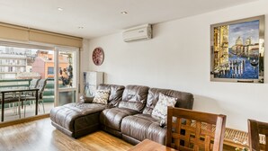A modern living room with a leather sofa, a dining table, and a cityscape painting. - Apartment 'Calonge Beach' with Private Terrace, Balcony and Air Conditioning (St Antoni de Calonge)