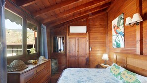 Ein Zimmer mit Holzboden, einem Bett, einem Schminktisch und einem Fenster mit Vorhängen.