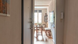 A hallway leading to a dining area with a wooden floor, a door on the left, and a wall-mounted light fixture. - Apartment 'Mirasole House' with Wi-Fi and Air Conditioning (bologna)