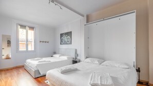 A bedroom with two beds, a bicycle artwork on the wall, a window, and a door. - Apartment 'Mirasole House' with Wi-Fi and Air Conditioning (bologna)