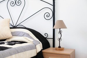 A bed with a black metal headboard, a bedside table with a lamp, and a drawer.