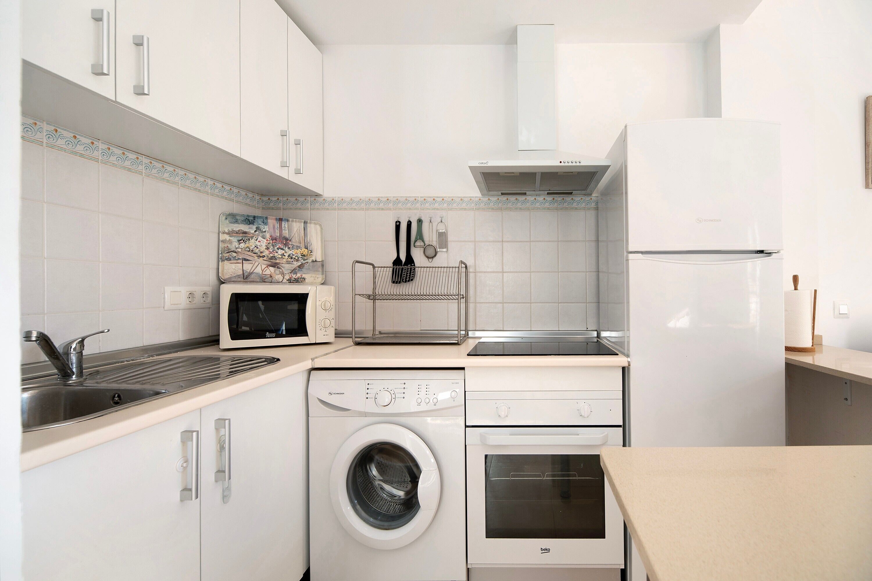 Uma cozinha compacta com máquina de lavar, forno, micro-ondas e frigorífico.
