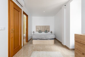 A bedroom with a bed, wooden wardrobe, and a white wall. - Apartment 'Atico Duplex Con Terraza' with Sea View, Wi-Fi and Air Conditioning (manilva)