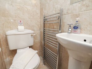 Un bany amb vàter, assecador de mans i un lavabo amb dispensador de sabó.