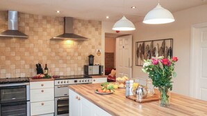 Een moderne keuken met een houten aanrecht, roestvrijstalen apparatuur en hangende lampen.