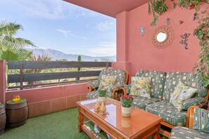 A balcony with a sofa, a wooden table, and decorative items.