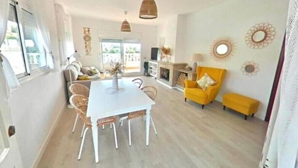 Un vaste espace de vie comprenant une table à manger, des chaises, un fauteuil jaune et un canapé.
