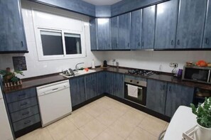 A kitchen with blue cabinets, a dishwasher, a stove, and a microwave.