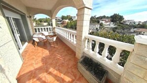 Un balcon doté d’un sol carrelé, d’une balustrade blanche et offrant une vue sur les environs.